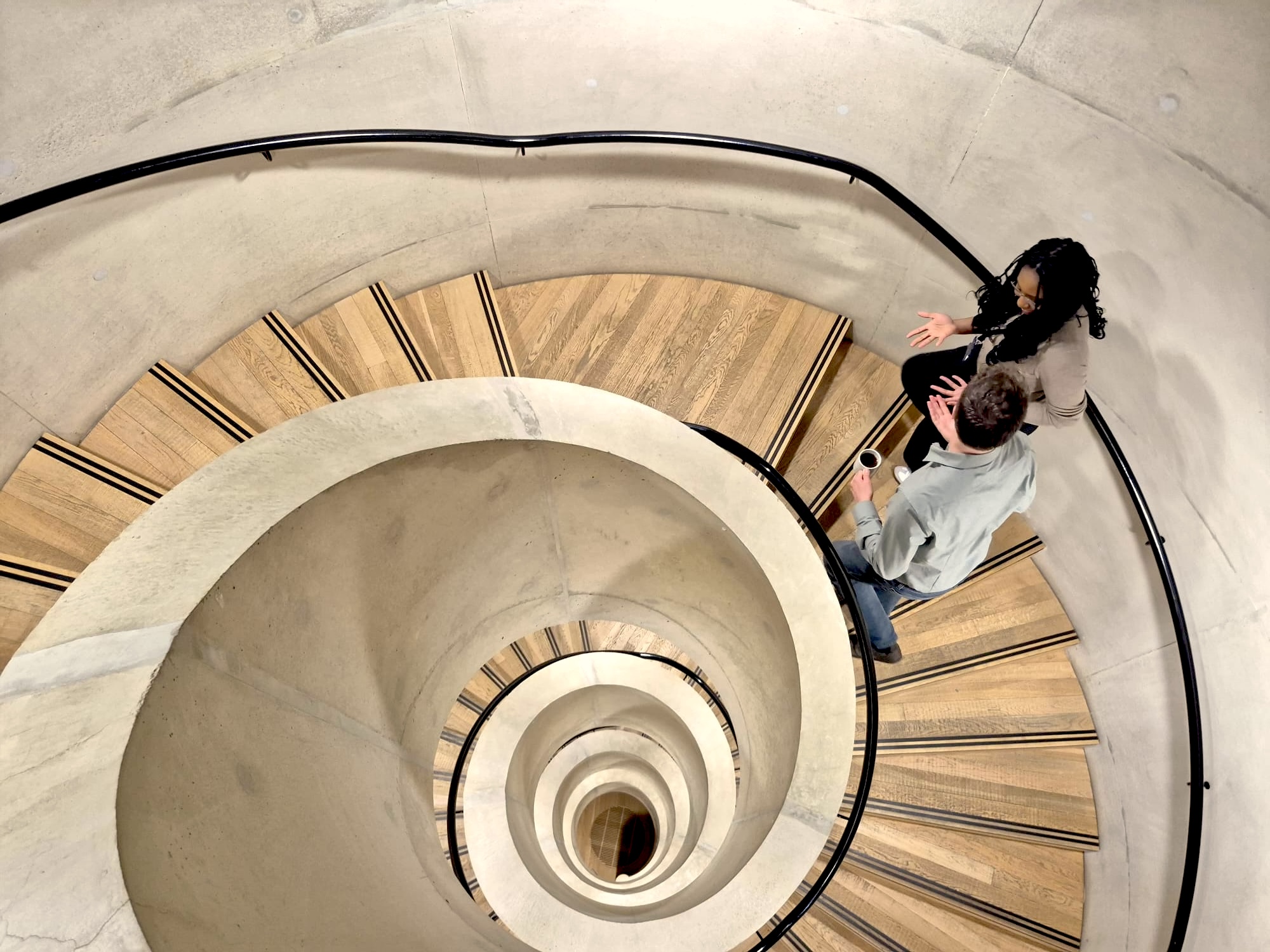 People walk up a spiral staircase in the Blavatnik School of Government